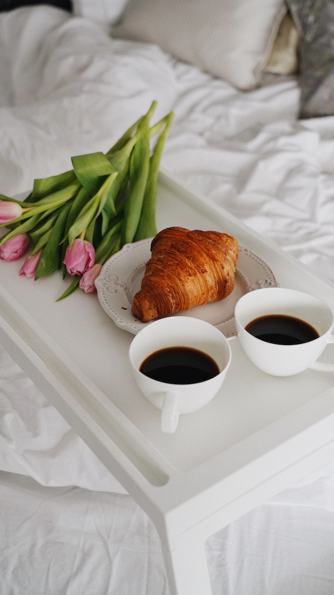 Breakfast in Bed with Croissant, Coffee and Bunch on Pink Tulips 